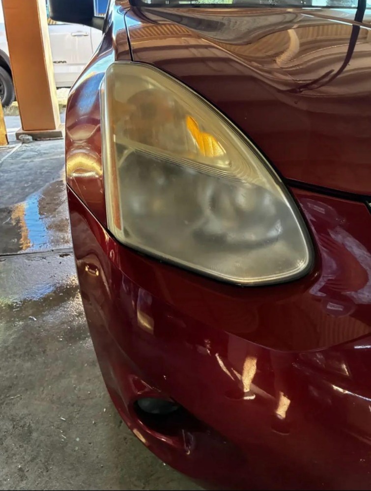 Oxidized, cloudy yellow headlight on a red sedan before restoration